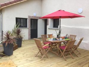 a table and chairs with a red umbrella on a patio at Gîte de la Taillanderie in Hauterives