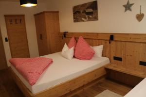 een slaapkamer met een bed met rode en witte kussens bij Apart Gerlossteinblick in Aschau