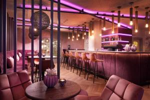 a bar with purple lighting and a table and chairs at Adler Inn Tyrol Mountain Resort SUPERIOR in Tux