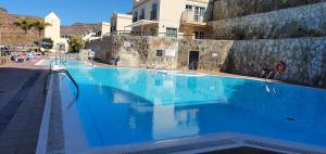 a large blue swimming pool in front of a building at Beautiful duplex with jacuzzi in Puerto Rico de Gran Canaria
