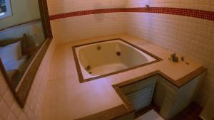 a bath tub in a bathroom with a tiled floor at POUSADA DAS ORQUIDEAS20 in Guapimirim