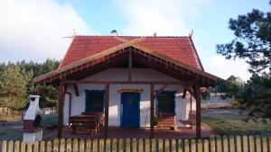 a small house with a red roof and a fence at Domek Smerfna Chatka in Wąglikowice +7 photos