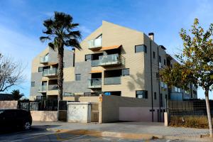 a tall building with a palm tree in front of it at APARTAMENTO AMPLIO. VISTAS A LA PLAYA in Puzol