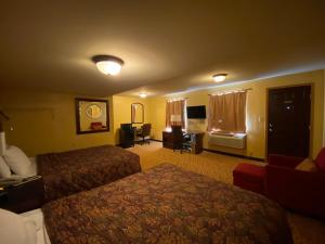 une chambre d'hôtel avec deux lits et un canapé dans l'établissement Regal Inn Coffeyville, à Coffeyville