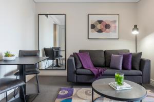 a living room with a couch and a table at Avani Metropolis Auckland Residences in Auckland