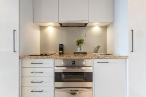 a kitchen with white cabinets and a stove at Avani Metropolis Auckland Residences in Auckland