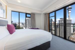 um quarto com uma cama grande e janelas grandes em Avani Metropolis Auckland Residences em Auckland