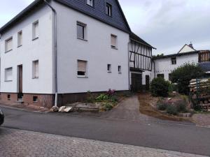 a white house with a black roof on a street at Ferienhaus Cilla in Beltheim