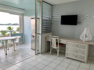 une pièce avec un bureau et une télévision au mur dans l'établissement Ti Bleu • Studio vue mer & accès plage, au Gosier