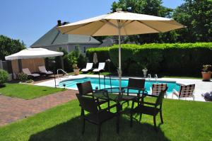 uma mesa e cadeiras debaixo de um guarda-sol ao lado de uma piscina em Harbor Light Inn em Marblehead