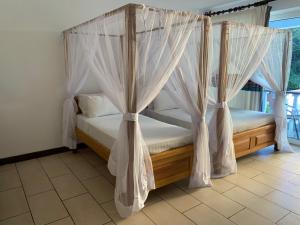 Elegant Studio Bamburi Beach في مومباسا: غرفة نوم بسرير مظلة مع ستائر بيضاء