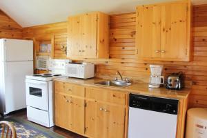 a kitchen with wooden cabinets and a white appliance at Avonlea Cottages in Cavendish