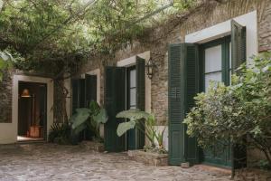 a stone house with green shutters and trees at Posada Plaza Mayor in Colonia del Sacramento