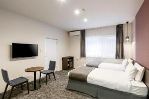 um quarto de hotel com uma cama e uma televisão de ecrã plano em M's Hotel Kyoto Station Kasuga em Quioto