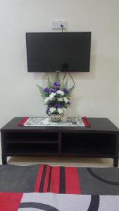 a black table with a vase of flowers on it at Homestay AlFaruqi Gambang 1 in Gambang