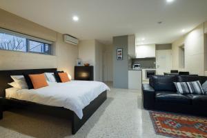 a bedroom with a bed and a couch and a kitchen at Saudade Margaret River in Margaret River Town