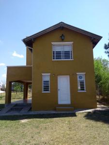 una pequeña casa amarilla con una puerta blanca en Los Horneros in 