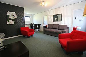 - un salon avec des chaises rouges et un canapé dans l'établissement Forgotten World Motel, à Taumarunui