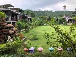 a yard with umbrellas in the grass next to houses at Baan Boom Boxes Eco Friendly Resort in Mae Nam