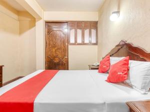 a bedroom with a bed with red and white pillows at Hotel Esperanza, Oaxaca Centro in Oaxaca City