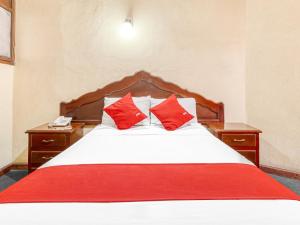 a bedroom with a bed with two red pillows at Hotel Esperanza, Oaxaca Centro in Oaxaca City