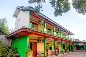 Dieses grüne und orangefarbene Gebäude verfügt über einen Balkon. in der Unterkunft SUPER OYO 1788 House 24 in Yogyakarta