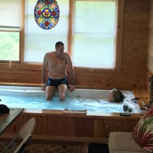 un hombre en una bañera con una mujer en ella en PRIVATE Log Cabin with Indoor pool sauna and gym YOU RENT IT ALL NO ONE ELSE, en McAlpin