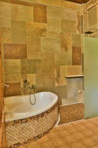 a bathroom with a tub and a tiled wall at Hotel San Bada Resort & Spa in Manuel Antonio