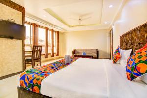 a bedroom with a large bed and a chair at FabHotel CT Palace New Market in Bhopal