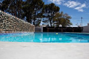 a swimming pool with blue water and a stone wall at French Karoo Guesthouse in Beaufort West