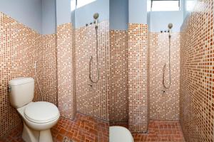 a bathroom with a toilet and tiled walls at SUPER OYO 2209 Solo Point Guest House Syariah in Solo