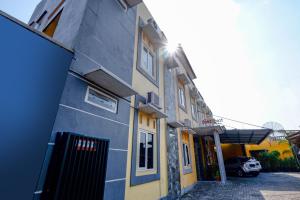 a blue and yellow building with a car parked next to it at Hotel O Solo Point Guest House Syariah in Solo