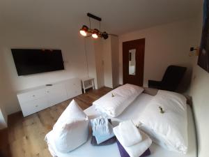 a bedroom with a white bed with pillows and a flat screen tv at Apart Tuxertal in Finkenberg