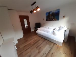 a bedroom with a white bed and wooden floors at Apart Tuxertal in Finkenberg