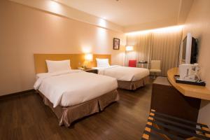a hotel room with two beds and a television at Garden Villa in Kaohsiung