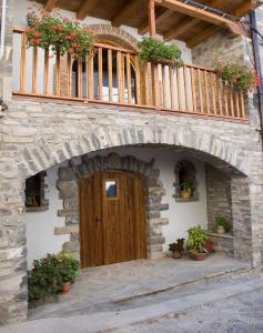 a stone house with a wooden door and a balcony at La Portada Del Medievo II - Apartamentos in Javierregay