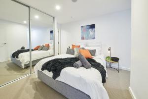 una camera con due letti e uno specchio di Mega Style Apartments Opus a Melbourne