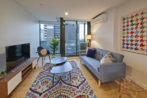 un soggiorno con divano e TV di Mega Style Apartments Opus a Melbourne