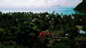 a view of the ocean and a house in the trees at Kame House Hostel in El Nido