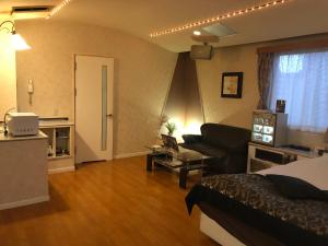 1 dormitorio con 1 cama y sala de estar con sofá en Restay Penthouse (Adult Only), en Kitakyushu