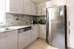 a kitchen with white cabinets and a stainless steel refrigerator at Frank Porter - Mon Reve in Dubai