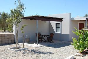 un patio avec une table et des chaises sous un toit dans l'établissement Longacre Olive & Vineyard Estate, à Langebaan