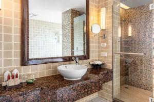 uma casa de banho com um lavatório, um espelho e um chuveiro em Garden Cliff Resort And Spa em Pattaya North
