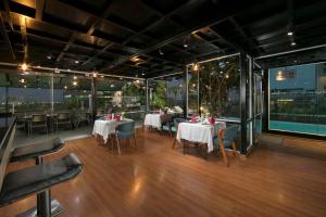 - un restaurant avec des tables, des chaises et de grandes fenêtres dans l'établissement La Casa Hanoi Hotel, à Hanoï