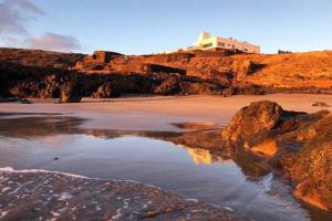 a beach with rocks and a building on a hill at Playa Marina Ocean View Eco Bungalow in Arrieta