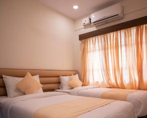 门格洛尔Hotel Sharda Residency的带窗户的酒店房间里有两张床