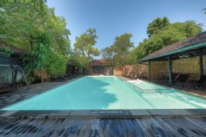 a large blue swimming pool with chairs and trees at The RiverKwai Bridge Resort in Kanchanaburi City