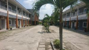 an empty street with palm trees in front of buildings at Liberty Homestay in Parit
