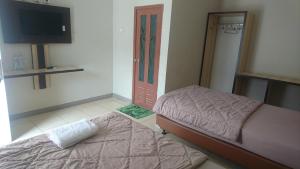 sypialnia z dwoma łóżkami, telewizorem i drzwiami w obiekcie Liberty Homestay w mieście Parit