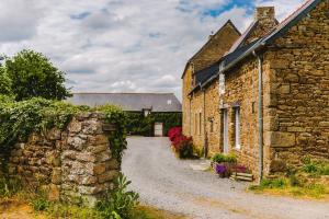 an old stone house with a stone wall and a street at La Ville Tanet in Landéhen